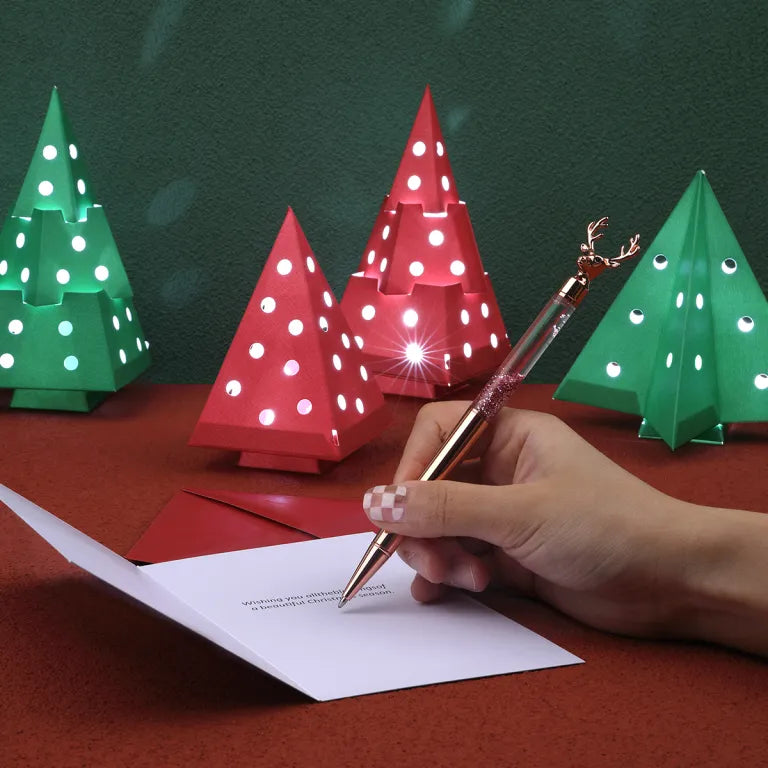 Hand writing a letter with decorative Christmas trees in the background